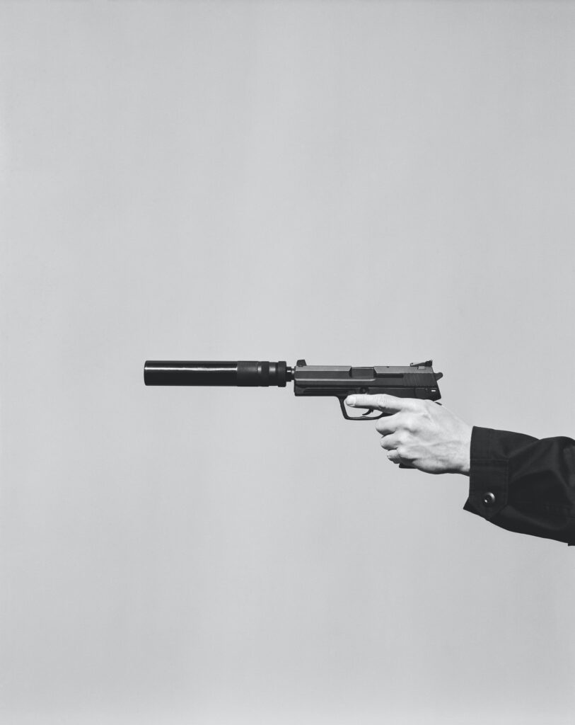 Detail of man aiming high powered hand gun with silencer