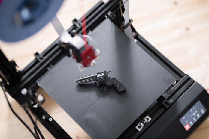 Overview of black revolver gun on working surface of 3d printer on table