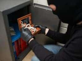 thief stealing valuables from safe at crime scene