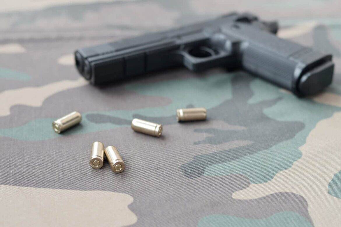 9mm bullets and pistol lie on camouflage green fabric. A set sho